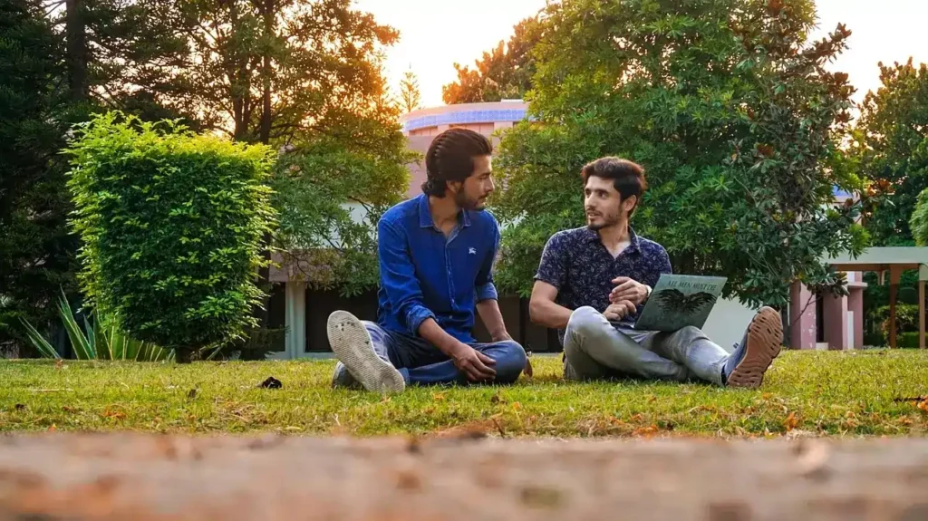 Pakistani students sitting and studying in a UK university ground.