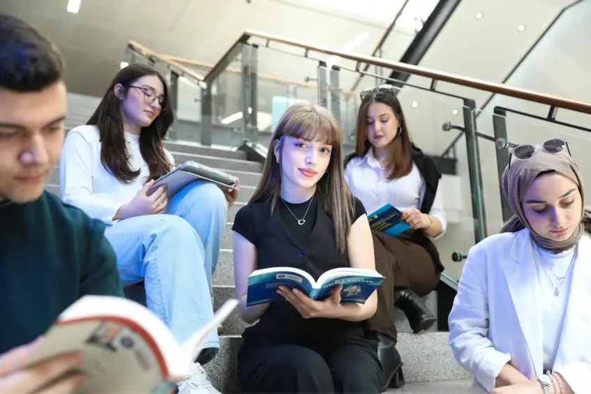 Pakistani students sitting on university stairs and reading