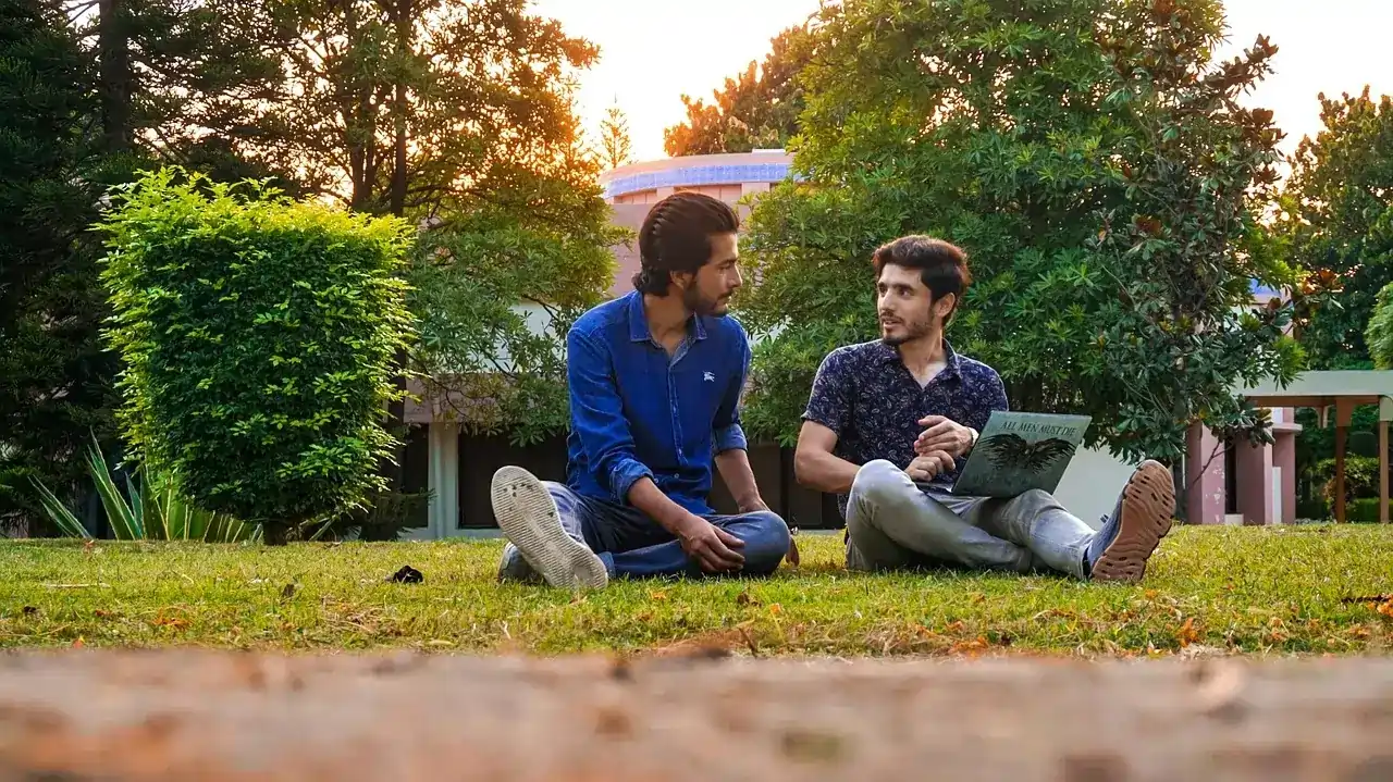 Pakistani students sitting and studying in a UK university ground.