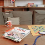Student preparing for IELTS Life Skills A2 exam with study book and practice materials in a study room